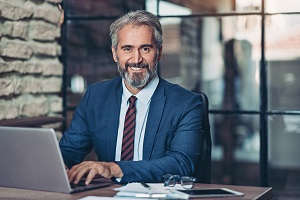 businessman on laptop smiling at camera